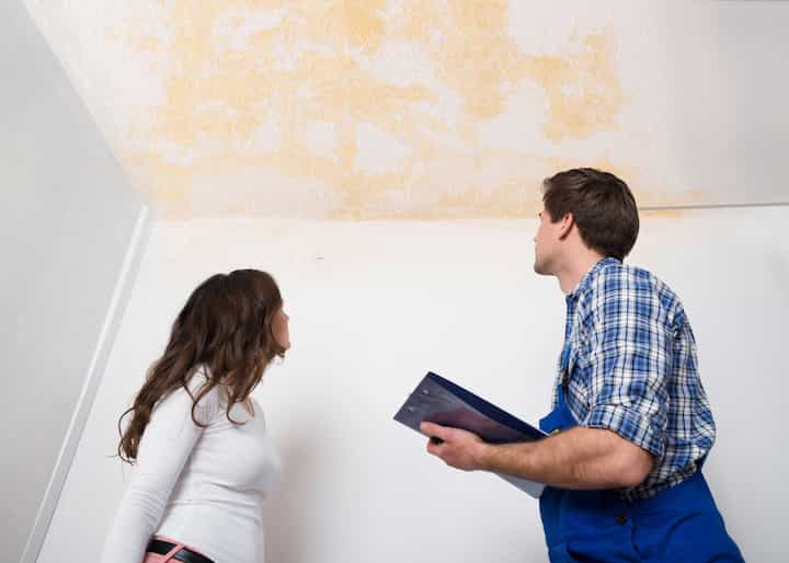 A water damage expert doing an assessment and inspection with a woman who has damaged ceiling caused by a water leak in Brandon, FL